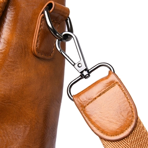Detailed macro view of the dark chrome metal hook and brown lychee grain leather strap
