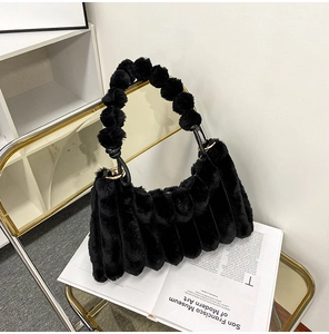 Close-up of black faux fur bag with vertical pleats and decorative pom-pom handle detail