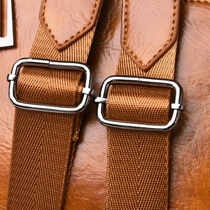 Detail of adjustable nylon strap and metal buckle on brown faux leather backpack