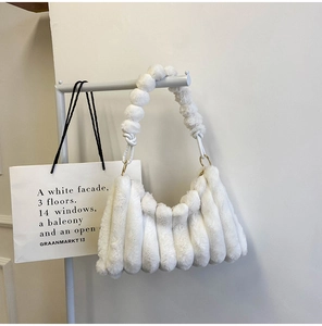 Detail of white fluffy faux fur underarm bag with unique plush ball shoulder strap