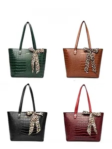 Color display of embossed bucket bags in green, brown, black and red with silk scarves