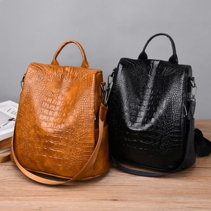 Detail of brown and black crocodile embossed texture backpacks with dark metal hardware