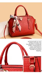 Close-up of red crocodile embossed leather handbag with silk scarf and gold hardware detail