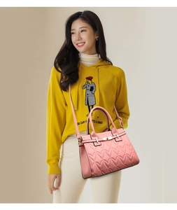Detailed view of pink heart-quilted leather handbag with golden twist lock and strap