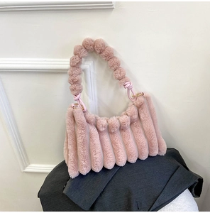 Detail of pink plush handbag featuring vertical striped faux fur and beaded ball handle
