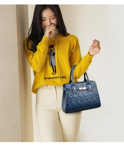 Blue quilted handbag detail with V-shaped stitching and golden twist lock closure