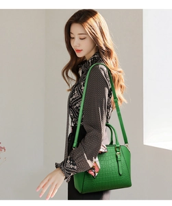 Detail of green crocodile embossed handbag featuring a stylish silk scarf and metal hardware
