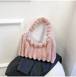 Detail of pink faux fur handbag showing plush pom-pom handle and vertical striped texture