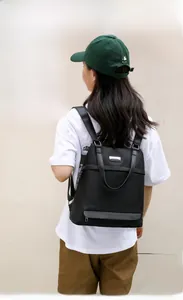 Black nylon backpack on model showing large capacity for A4 magazines in outdoor street setting