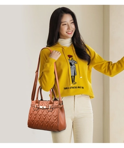 Close-up of caramel quilted leather shoulder bag with gold metal hardware and top handles