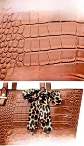Detail of brown crocodile embossed bucket bag with metal logo and leopard print silk scarf