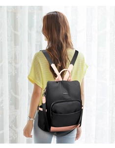 Vue détaillée d'une femme portant le sac à dos en nylon noir avec accents roses