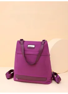 Detail of deep purple Oxford nylon backpack showing water-resistant texture and front zip pocket