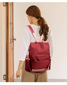 Vue détaillée d'un sac à dos en nylon bordeaux avec sangles roses et poche latérale