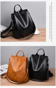 Detail showing crocodile texture leather backpacks in black and brown with dual zippers