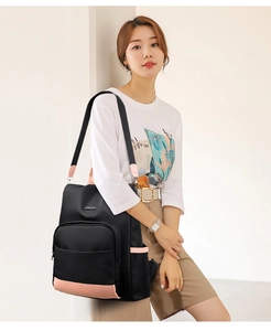 Détail du sac à dos en nylon montrant la base en cuir rose et le logo JINGPIN en métal