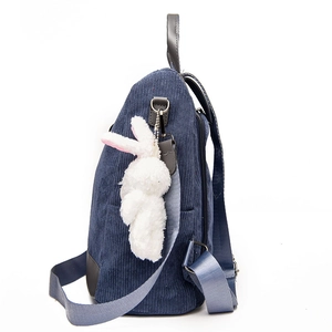 Side view of navy blue corduroy backpack for women with a cute white bunny plush pendant