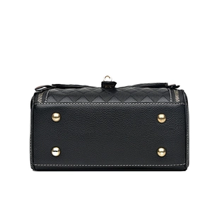 Vue de dessous du sac à main en cuir noir avec clous dorés et coutures blanches apparentes