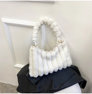 Detail of white plush handbag featuring vertical pleated texture and metal ring handles