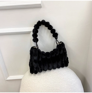 Detail of black faux fur shoulder bag featuring vertical pleated texture and furry handle