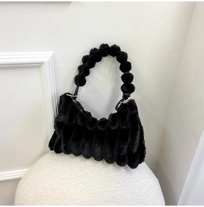 Detail of black plush handbag featuring unique spherical bubble handle and golden metal rings