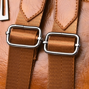 Detail of adjustable caramel brown leather and nylon shoulder straps with silver buckles