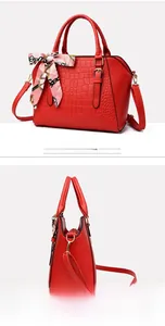 Detail of red embossed crocodile pattern handbag with silk scarf handle and gold hardware
