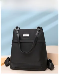 Close-up of black Oxford cloth backpack with leather handles and metal hardware detail