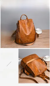 Detail of brown crocodile pattern PU leather backpack with adjustable straps on wood surface