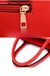 Detail of red faux leather handbag showing golden square zipper and soft handles