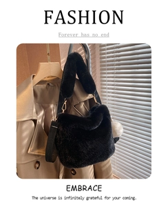 Detail of black faux fur bucket bag with plush pom-pom and gold metal hardware