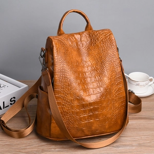 Brown crocodile pattern faux leather backpack and handbag displayed on a desk with coffee