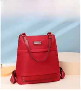 Detail of red oxford nylon backpack with horizontal zipper pocket and metal logo detail