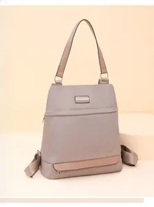 Detail of taupe Oxford fabric backpack showing adjustable straps and silver metal hardware