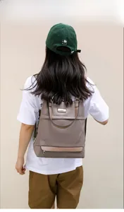 Brown nylon backpack detail showing the adjustable shoulder straps and carry handle