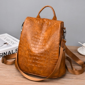 Detail of brown crocodile pattern PU leather backpack showing glossy texture and straps