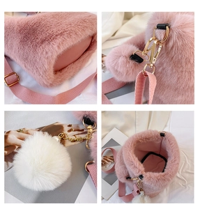 Detail view of pink faux fur bucket bag featuring golden hardware and a white pom-pom charm