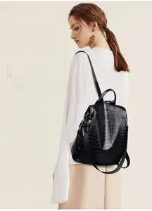 Detail of black crocodile pattern backpack with metallic buckle on white shirt model