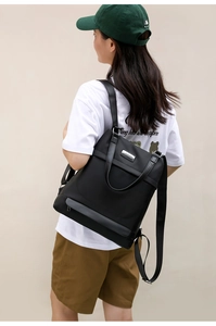 Detailed view of women's black oxford backpack showing top handles and durable metal zippers