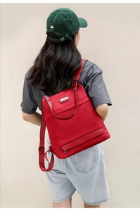 Detail of red water-resistant oxford backpack with silver logo and leather handle