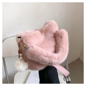Detail of pink faux fur bucket bag featuring a soft pom-pom and pearl charm with gold hardware