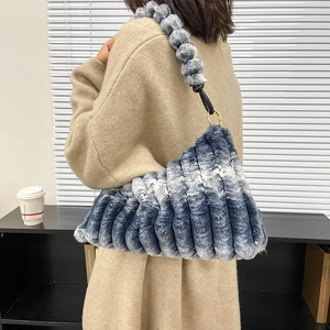 Plush shoulder bag with blue-white gradient and fuzzy ball strap in a side-view shot