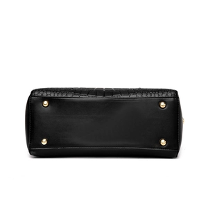 Bottom view of black leather handbag with crocodile pattern panels and gold protective feet