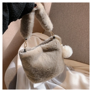 Detailed close-up of fluffy khaki faux fur bucket bag with pearl and pompom charm