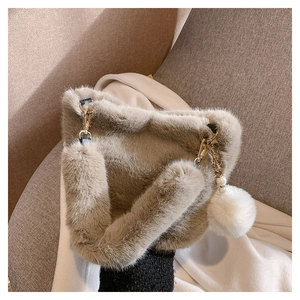 Detailed view of plush faux fur bucket bag with pearl and pompom charm in khaki color