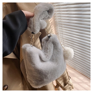 Detail of grey plush bucket bag showing soft faux fur texture and white pompom charm