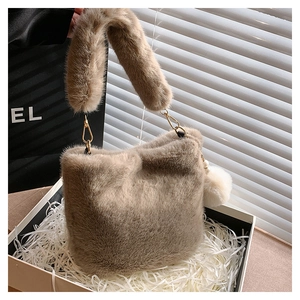 Close-up of khaki plush bucket bag with thick faux fur handle and golden hardware