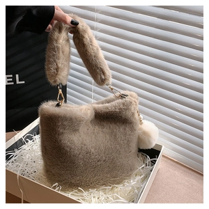 Close-up of light brown plush bucket bag with soft faux fur texture and white pompom