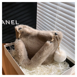 Detail of plush camel bucket bag with fluffy shoulder strap and pearl pompom charm