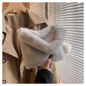 Detail of plush grey bucket bag with white faux fur pom-pom and soft winter texture